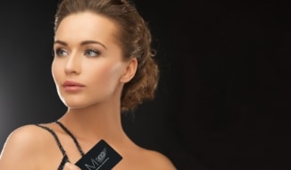 Close-up of a model wearing a black outfit and holding an M Spa business card